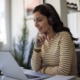 Young woman with bluetooth headphones attending an online class on her laptop